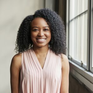 Young black business woman by window looking to camera